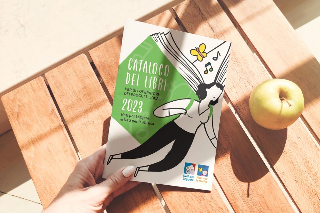 Layout Copertina Catalogo libri tenuta in mano e sullo sfondo un tavolo